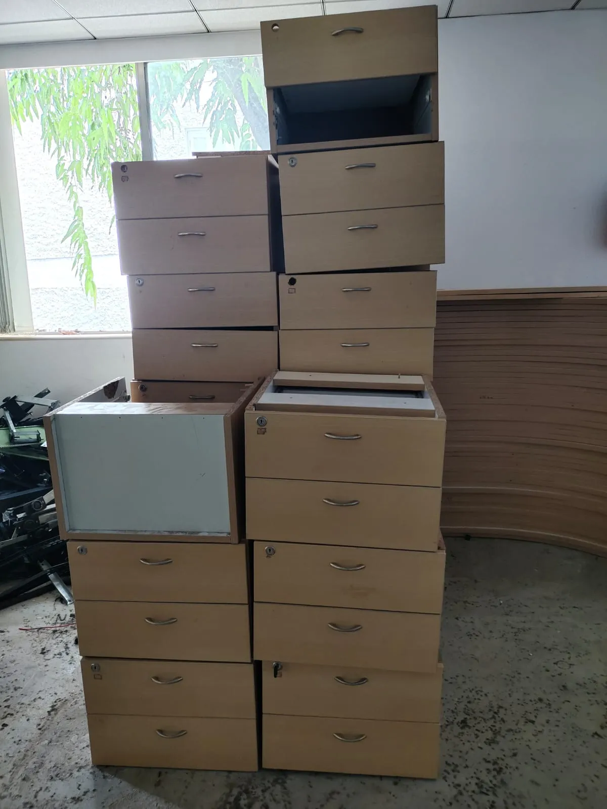 Office furniture dismantling showing stacked corporate filing cabinets and storage drawers prepared for scrap disposal or asset recovery.